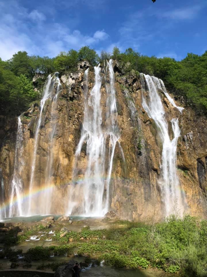 Cascading waterfalls with a rainbow along the wooden boardwalks of Plitvice Lakes National Park in Croatia.