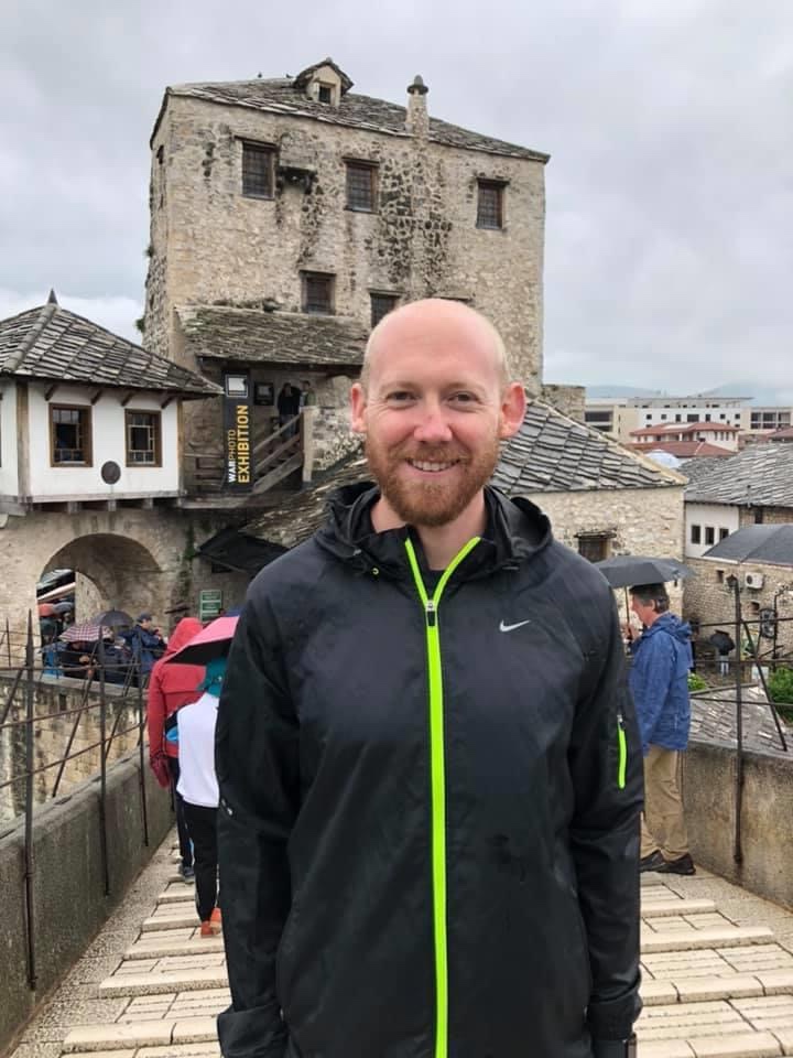 A man standing on a bridge in a black rain jacket. Located at the Stari Most Bridge in Mostar, Bosnia