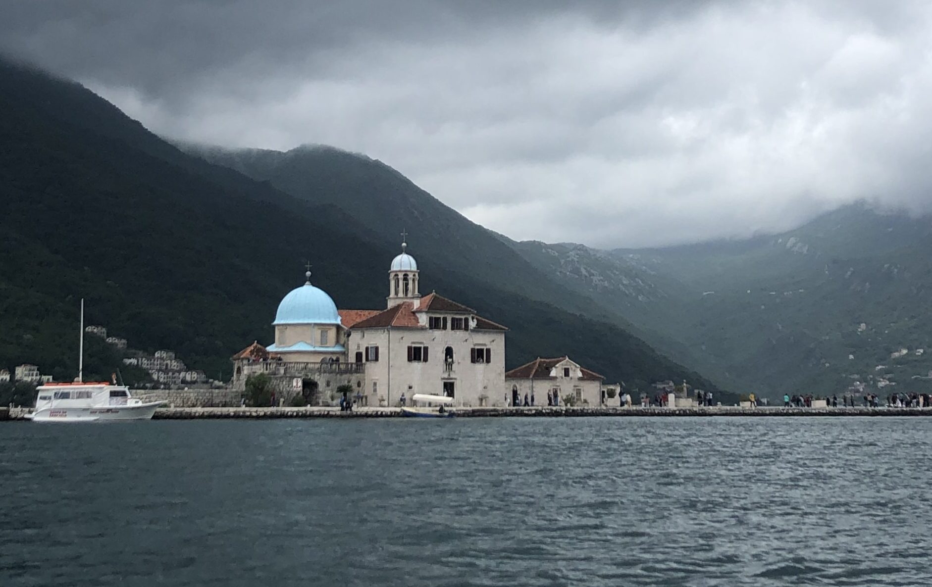 Our Lady of the Rocks, a small man-made island church in the Bay of Kotor, with its stone structure and blue dome surrounded by calm Adriatic waters.