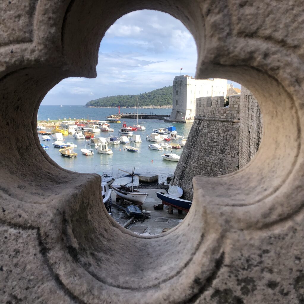 View of a harbor filled with boats framed by a stone archway.